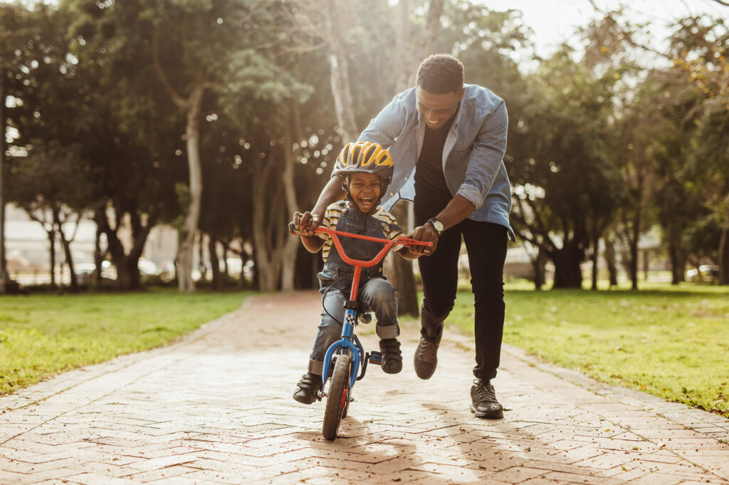 father teaching child how to ride a bike