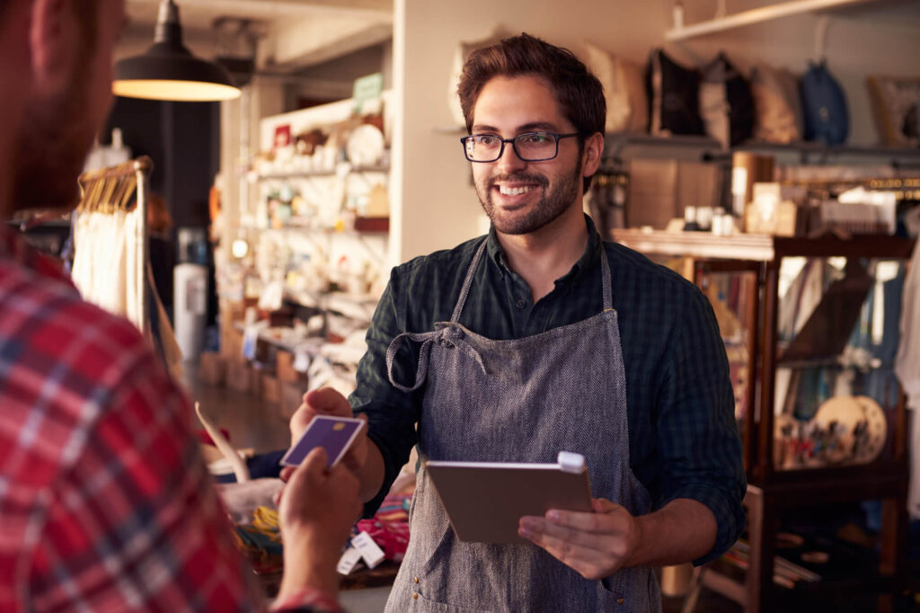 man taking payment on tablet in shop