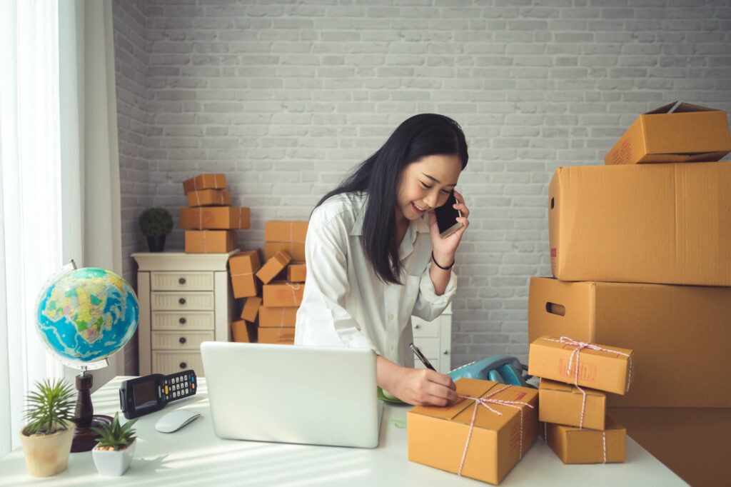 woman on phone call surrounded by cardboard boxes